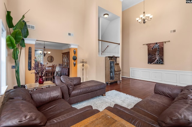 living room with a notable chandelier, a towering ceiling, visible vents, and dark wood-style flooring