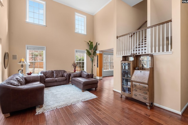 living area with baseboards, a high ceiling, and wood finished floors