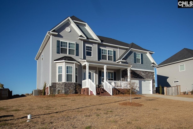 craftsman house with a front lawn, stone siding, a porch, concrete driveway, and an attached garage