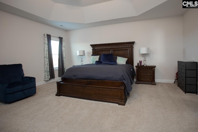 carpeted bedroom featuring a tray ceiling and baseboards