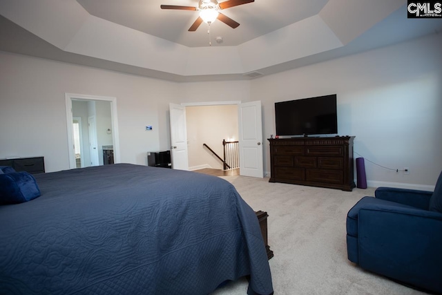 bedroom featuring visible vents, light carpet, a tray ceiling, baseboards, and ceiling fan