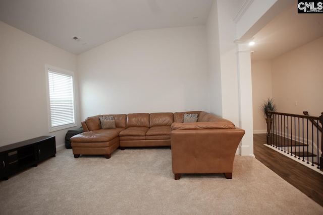 carpeted living area with baseboards, ornate columns, and vaulted ceiling