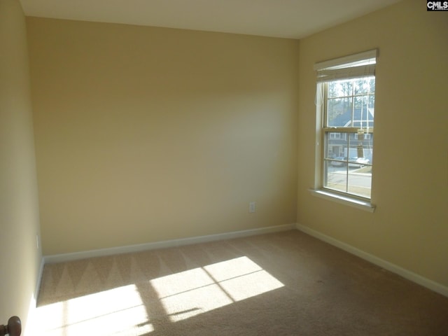 spare room featuring light colored carpet and baseboards