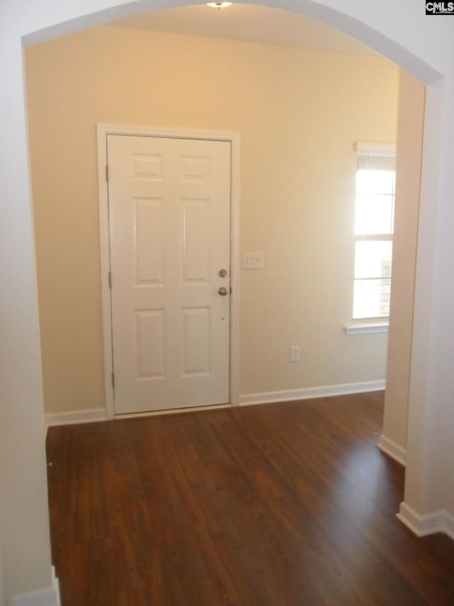 entryway featuring wood finished floors, arched walkways, and baseboards