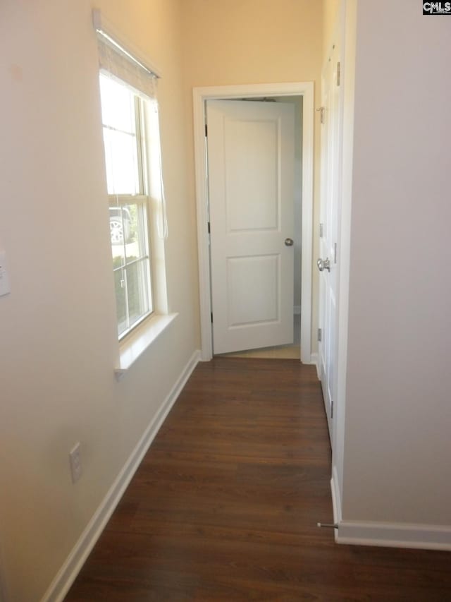 corridor with baseboards and wood finished floors