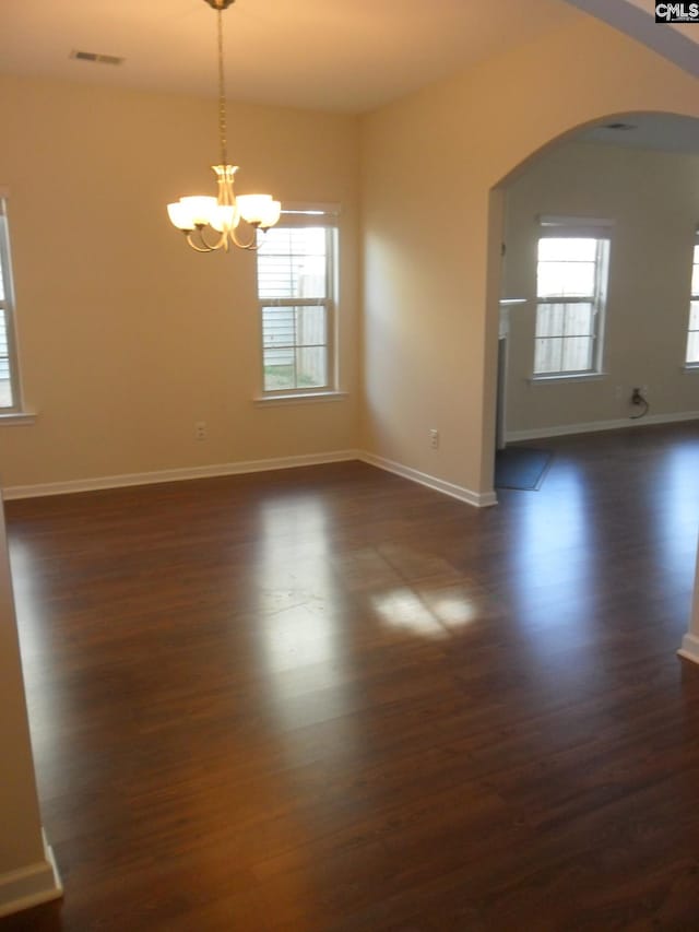 spare room with dark wood-style floors, visible vents, and a healthy amount of sunlight