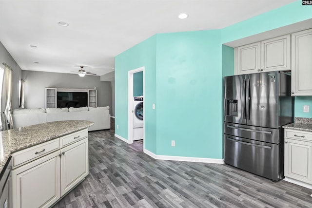 kitchen featuring baseboards, ceiling fan, wood finished floors, stainless steel fridge, and washer / clothes dryer