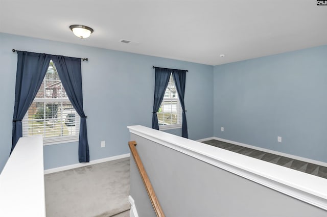 corridor featuring an upstairs landing, carpet flooring, visible vents, and baseboards