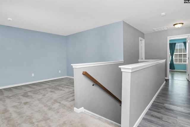 hall featuring visible vents, an upstairs landing, and baseboards