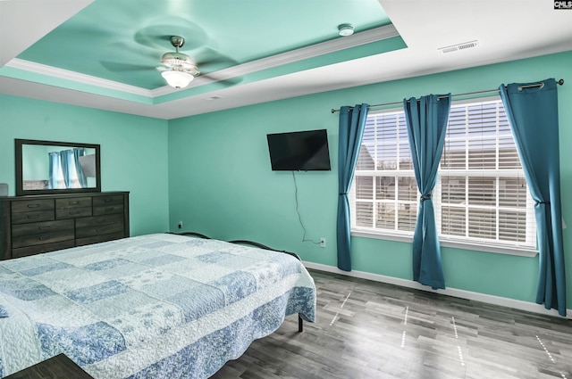 bedroom featuring visible vents, a raised ceiling, baseboards, and ornamental molding