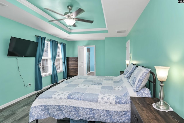 bedroom with visible vents, baseboards, a raised ceiling, and dark wood-type flooring