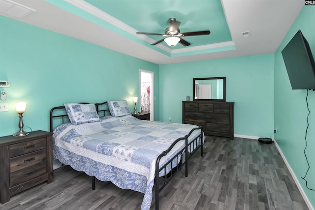 bedroom with visible vents, a ceiling fan, a tray ceiling, wood finished floors, and baseboards