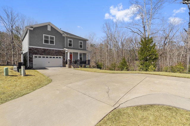 view of front of home with an attached garage, a front lawn, covered porch, stone siding, and driveway