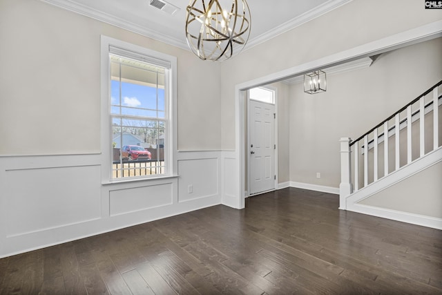 foyer featuring wood finished floors, an inviting chandelier, ornamental molding, and stairs