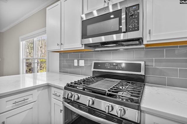 kitchen with decorative backsplash, white cabinets, ornamental molding, and stainless steel appliances