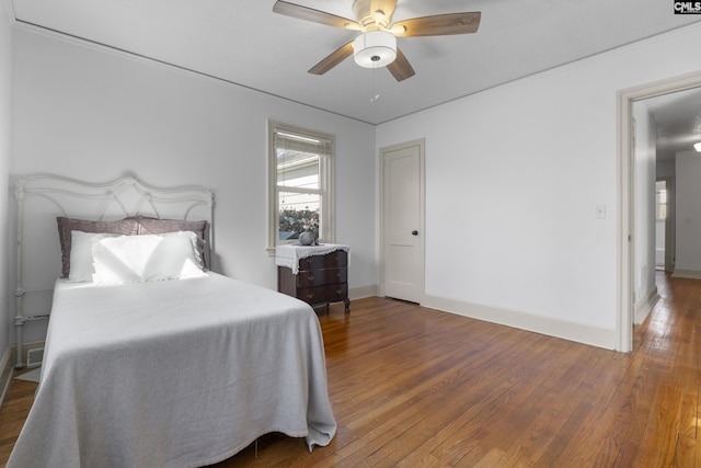 bedroom with hardwood / wood-style flooring, a ceiling fan, and baseboards