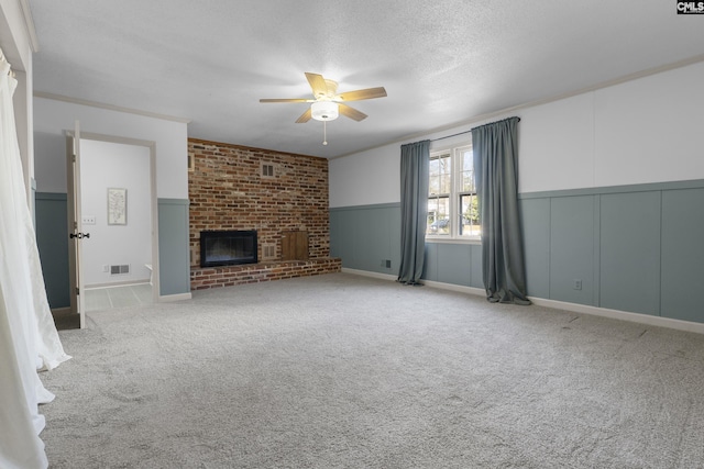 unfurnished living room featuring visible vents, a textured ceiling, carpet, crown molding, and a fireplace