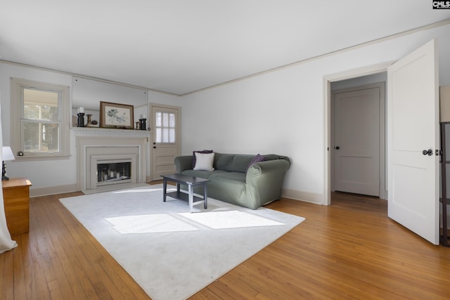 living room with light wood finished floors, a fireplace with flush hearth, and baseboards