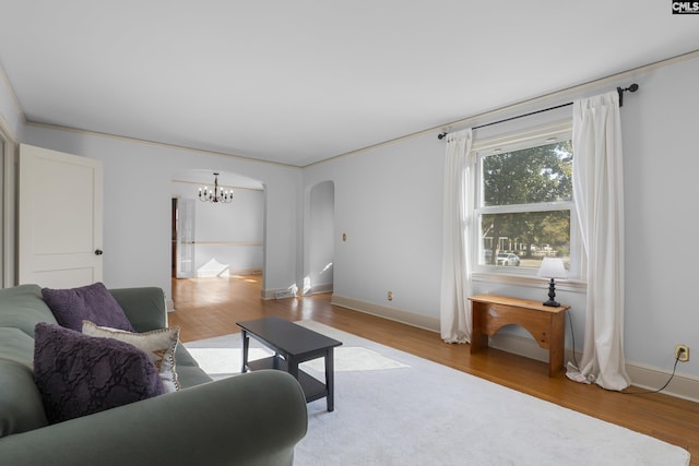 living room featuring arched walkways, a notable chandelier, baseboards, and wood finished floors