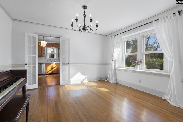 unfurnished dining area with a sink, visible vents, wood-type flooring, and baseboards