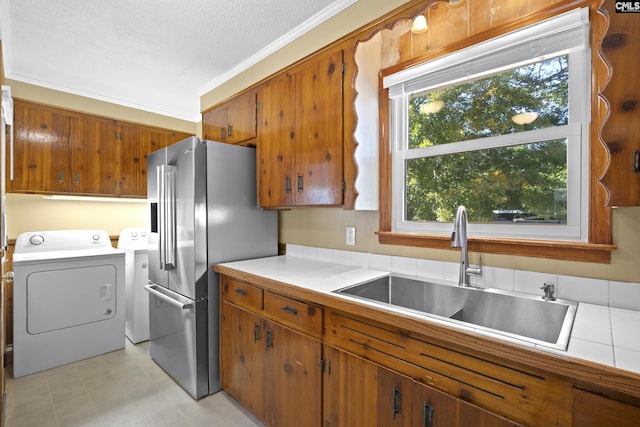 kitchen featuring separate washer and dryer, a sink, high end refrigerator, crown molding, and brown cabinets