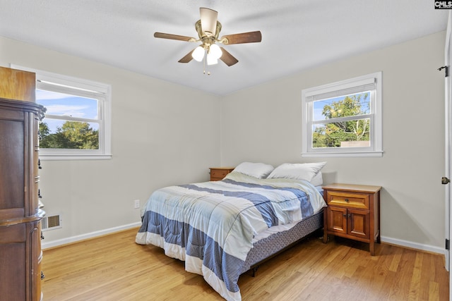 bedroom with baseboards, multiple windows, and light wood-style floors