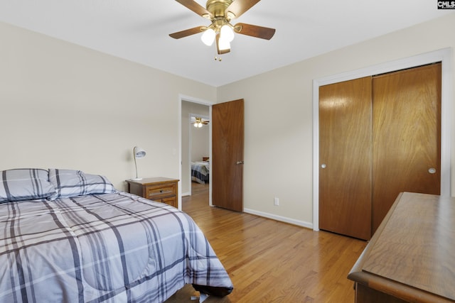 bedroom with a closet, baseboards, a ceiling fan, and light wood finished floors