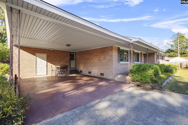 exterior space with crawl space, an attached carport, driveway, and brick siding