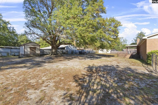 view of yard featuring an outbuilding, a storage unit, and fence