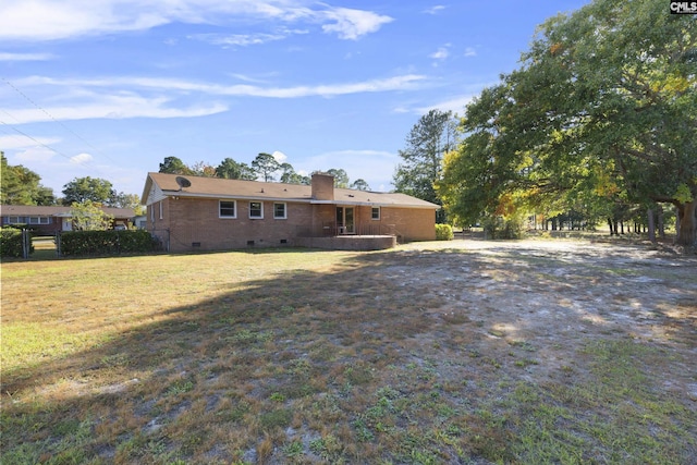 rear view of property with a yard, brick siding, a chimney, and crawl space