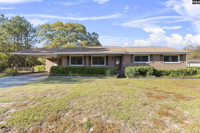 single story home featuring brick siding, an attached carport, driveway, and a front lawn