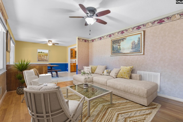 living room with visible vents, baseboards, wood finished floors, and a ceiling fan