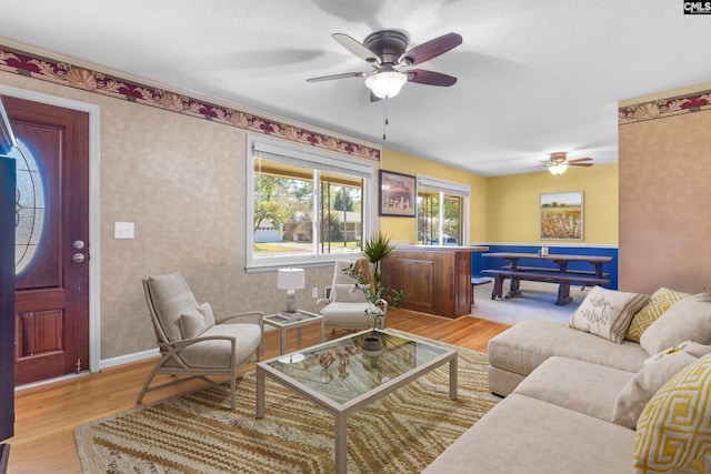 living room with ceiling fan, baseboards, a textured ceiling, and wood finished floors