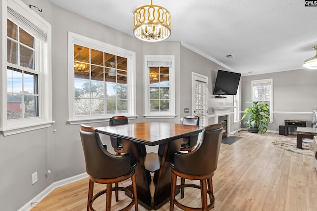 dining space with baseboards, visible vents, an inviting chandelier, a fireplace with flush hearth, and light wood-style floors