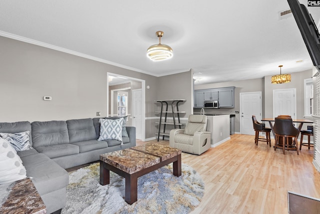 living room with light wood-type flooring, baseboards, visible vents, and ornamental molding