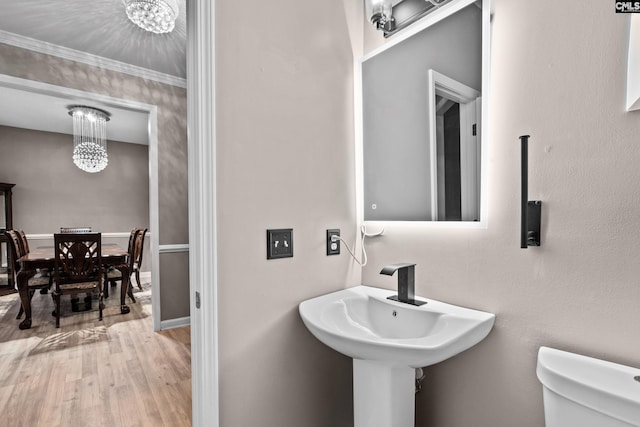 bathroom with toilet, wood finished floors, baseboards, and a chandelier