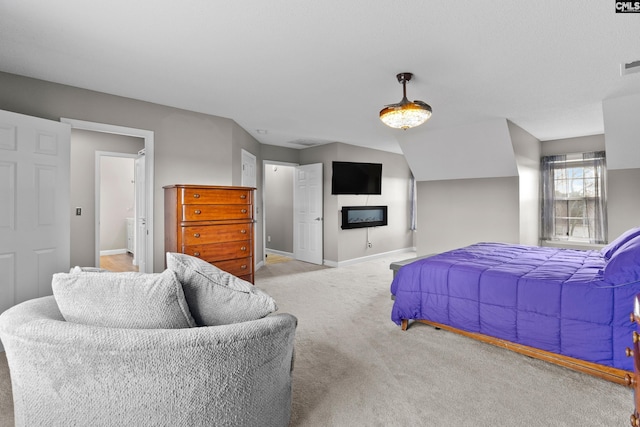 bedroom with a glass covered fireplace, carpet flooring, visible vents, and baseboards