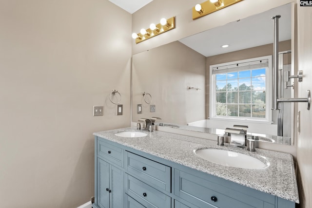 full bath with double vanity, baseboards, and a sink