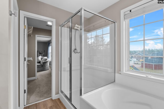 full bathroom featuring baseboards, wood finished floors, a bath, and a shower stall