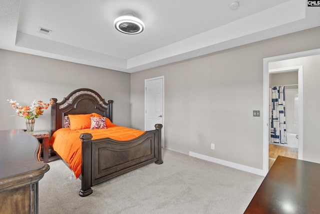 bedroom featuring visible vents, a raised ceiling, baseboards, and light carpet