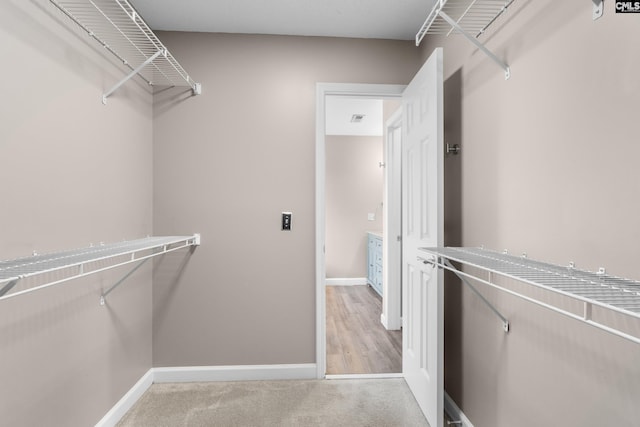 walk in closet with visible vents and light colored carpet