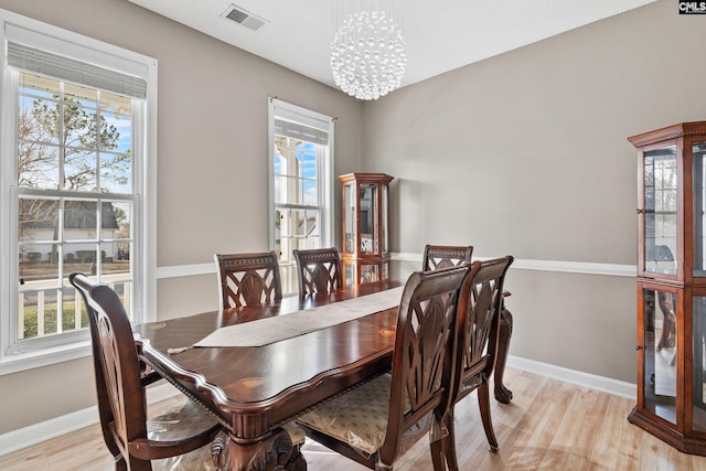 dining room featuring light wood finished floors, visible vents, a healthy amount of sunlight, and a chandelier