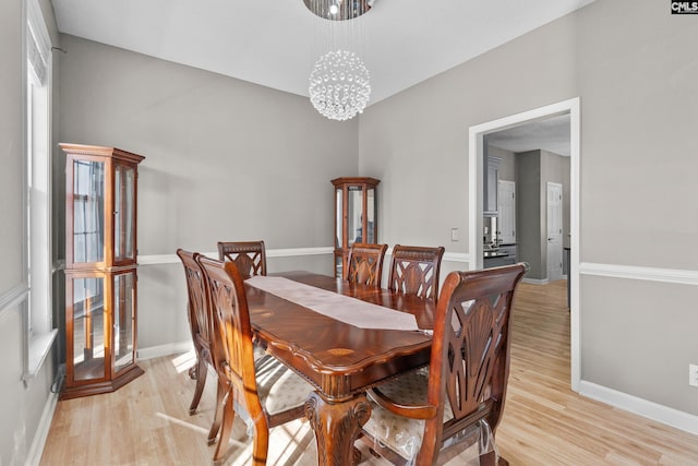 dining area featuring a notable chandelier, light wood-style flooring, and baseboards