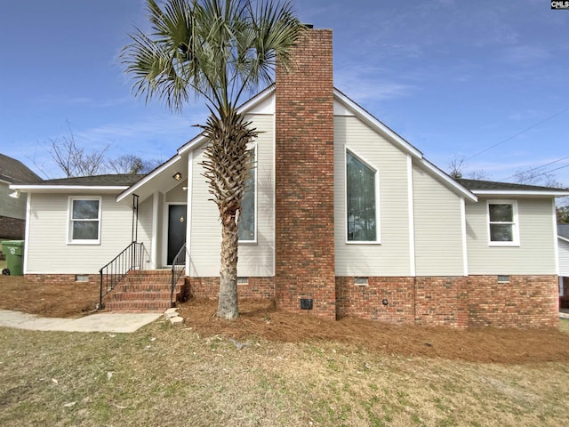 view of side of home with crawl space and a chimney