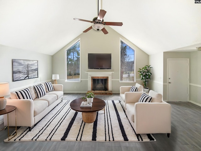 living area featuring wood finished floors, a fireplace, baseboards, ceiling fan, and vaulted ceiling