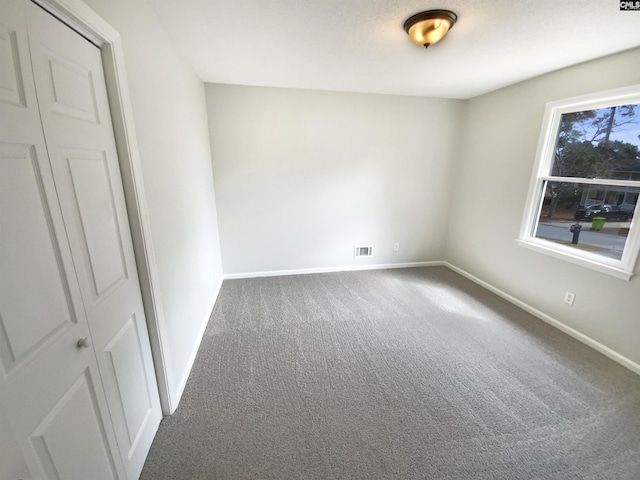 carpeted empty room featuring visible vents and baseboards