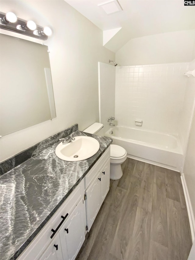 bathroom with shower / washtub combination, toilet, vaulted ceiling, wood finished floors, and vanity