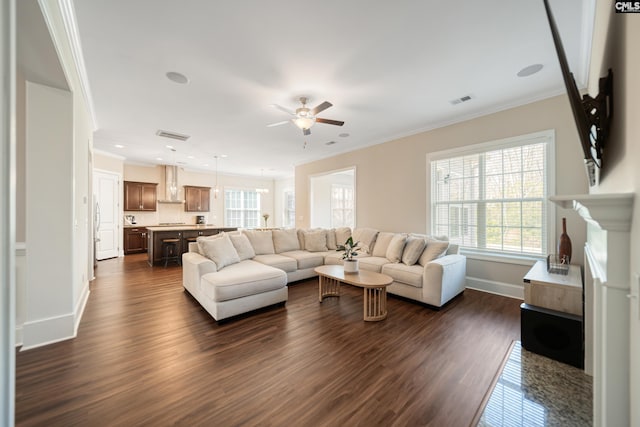 living room featuring a ceiling fan, baseboards, visible vents, dark wood-style flooring, and ornamental molding