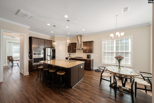 kitchen featuring visible vents, an inviting chandelier, stainless steel appliances, dark brown cabinets, and wall chimney range hood