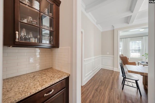 kitchen with dark brown cabinets, glass insert cabinets, beamed ceiling, light stone counters, and dark wood-style flooring